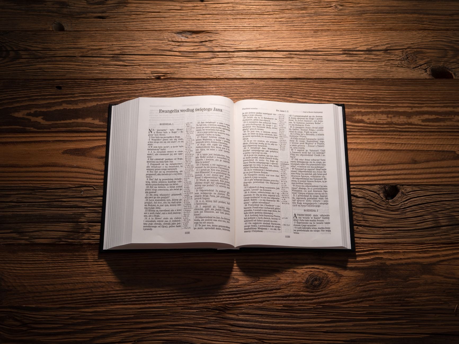 Open Bible on a warm wooden table in morning light, sacred text visible